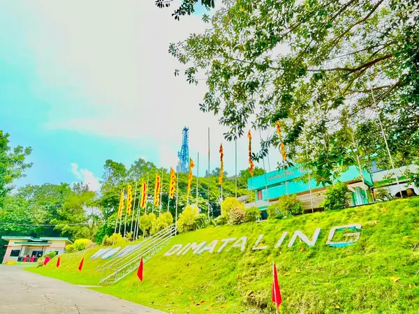 The white DIMATALING hillside letter sign on a green slope ringed with festival flags