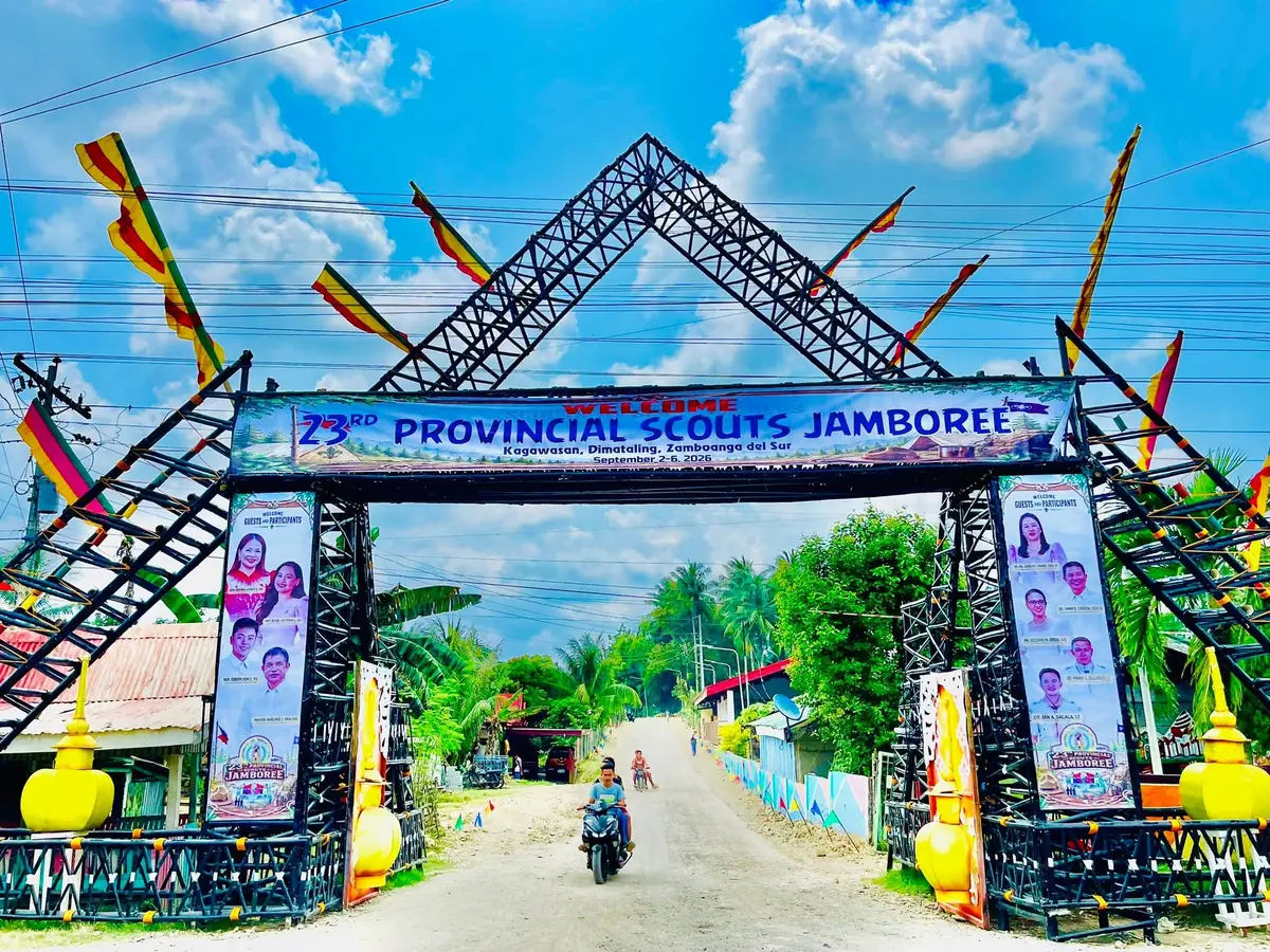 Steel welcome arch at Kagawasan draped with the 23rd Provincial Scouts Jamboree banner, a motorcycle passing beneath